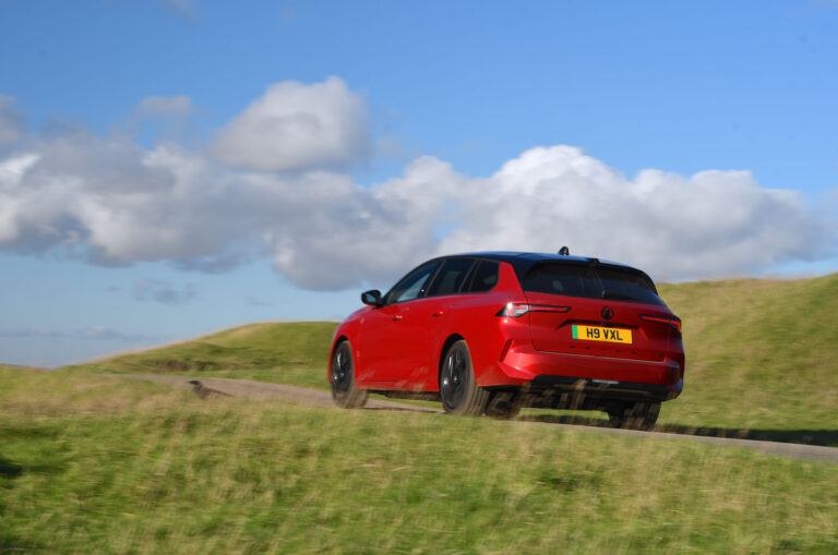 red vauxhall astra estate drives up a hill rear three quarters